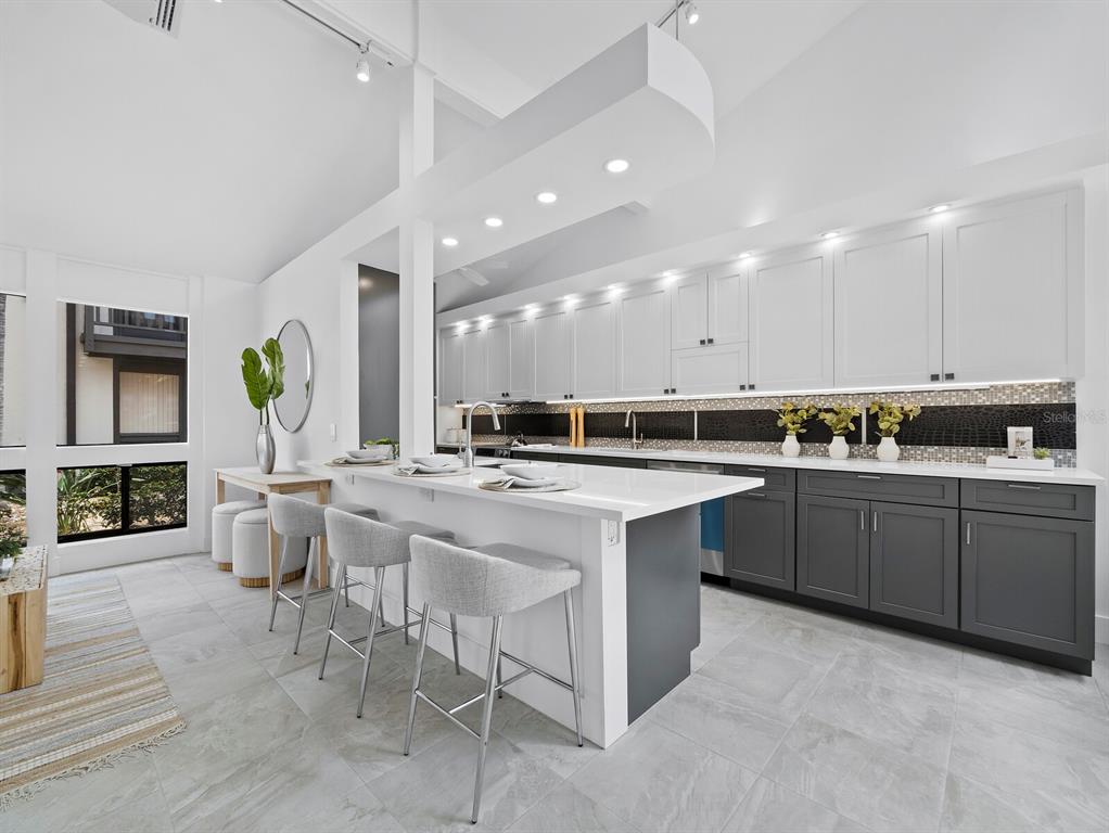 A modern kitchen features white upper cabinets, dark gray lower cabinets, and a white island — 800 S BLVD OF THE PRESIDENTS UNIT 19, SARASOTA, FL