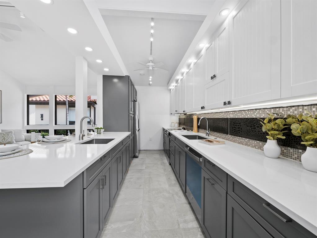 A modern kitchen features gray lower cabinets, white upper cabinets, and white quartz countertops — 800 S BLVD OF THE PRESIDENTS UNIT 19, SARASOTA, FL