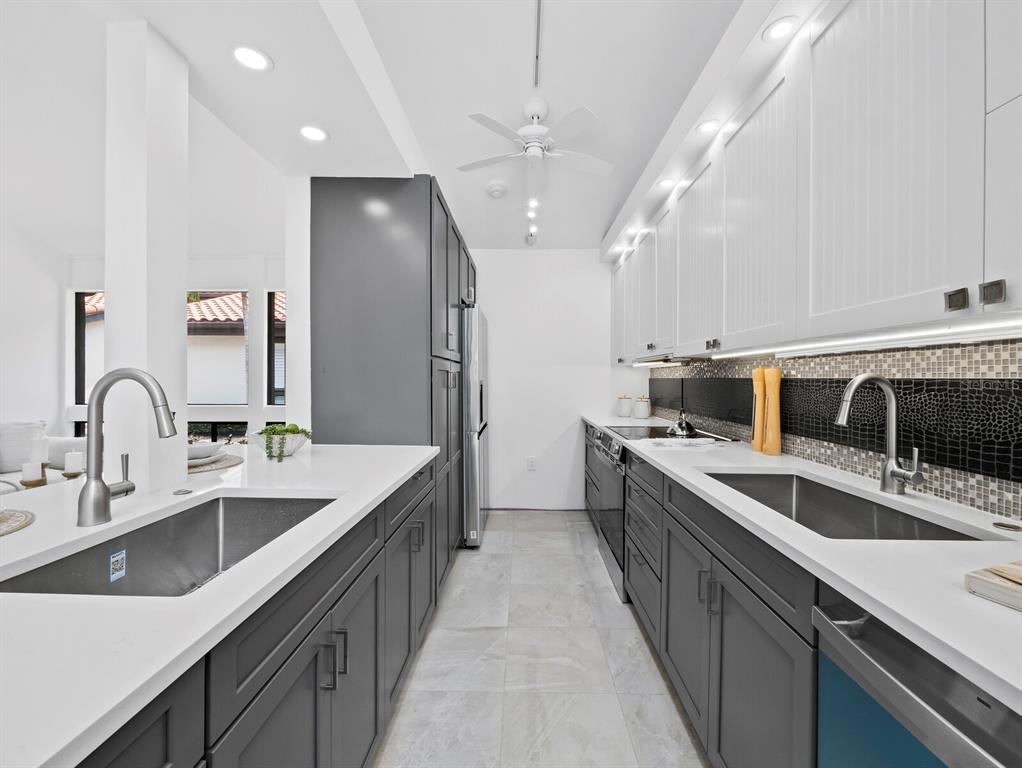A modern kitchen features dark gray lower cabinets, white upper cabinets, and white quartz countertops — 800 S BLVD OF THE PRESIDENTS UNIT 19, SARASOTA, FL