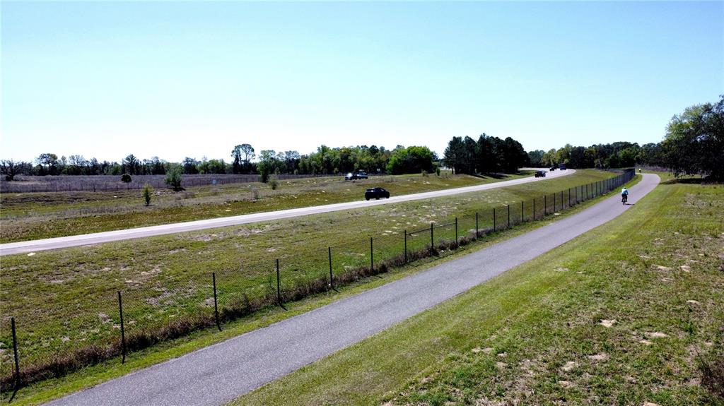 An aerial view shows a paved trail running parallel to a highway with a cyclist — 1290 ANDERSON SNOW ROAD, SPRING HILL, FL