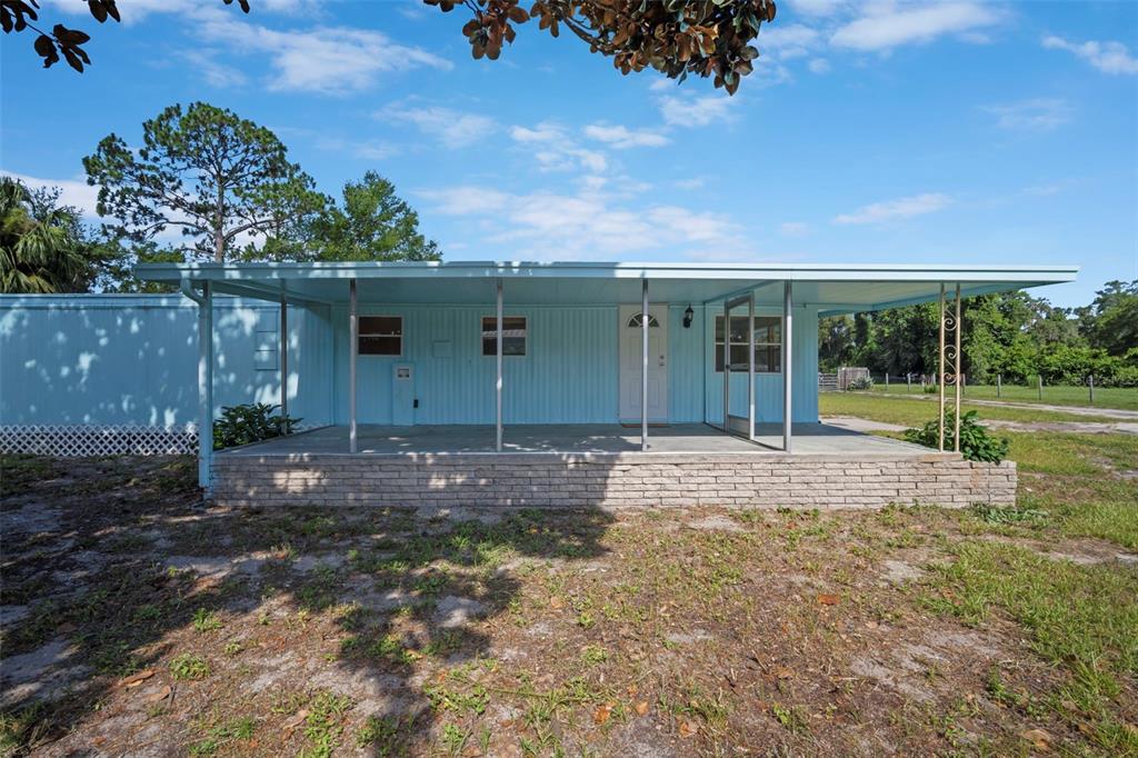 A light blue mobile home features a covered front porch with a brick base — 1389 NW 7TH LANE, LAKE PANASOFFKEE, FL