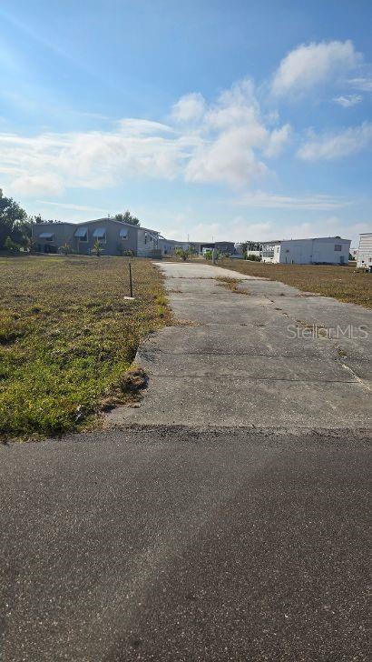 A concrete driveway leads toward a mobile home in an open, grassy residential area — 1365 SANDERLING DRIVE, ENGLEWOOD, FL