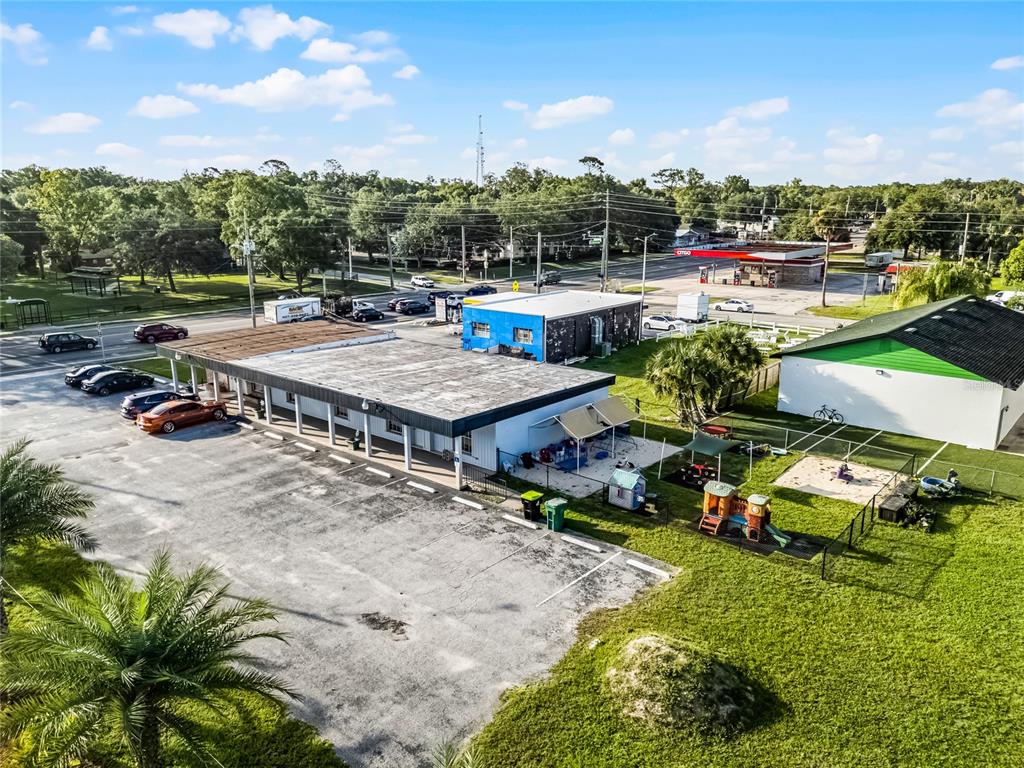 An aerial view shows a commercial building with a parking lot and a fenced playground — 465 S VOLUSIA AVENUE, ORANGE CITY, FL