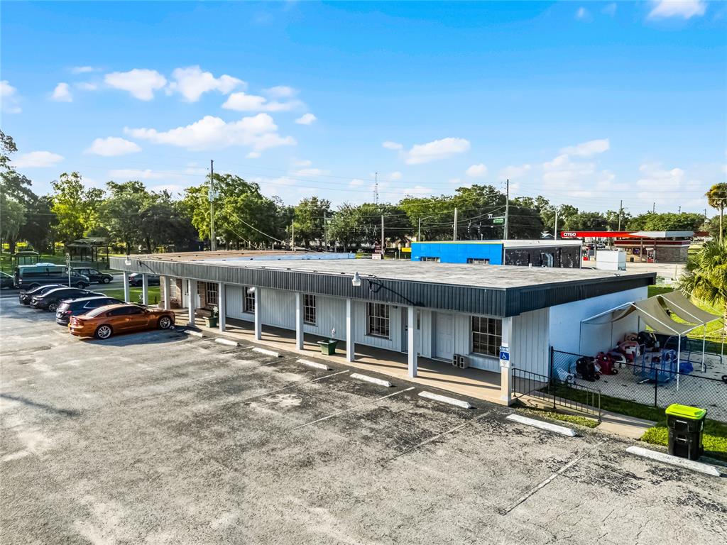 An aerial view shows a single-story commercial building with a parking lot and a fenced area — 465 S VOLUSIA AVENUE, ORANGE CITY, FL