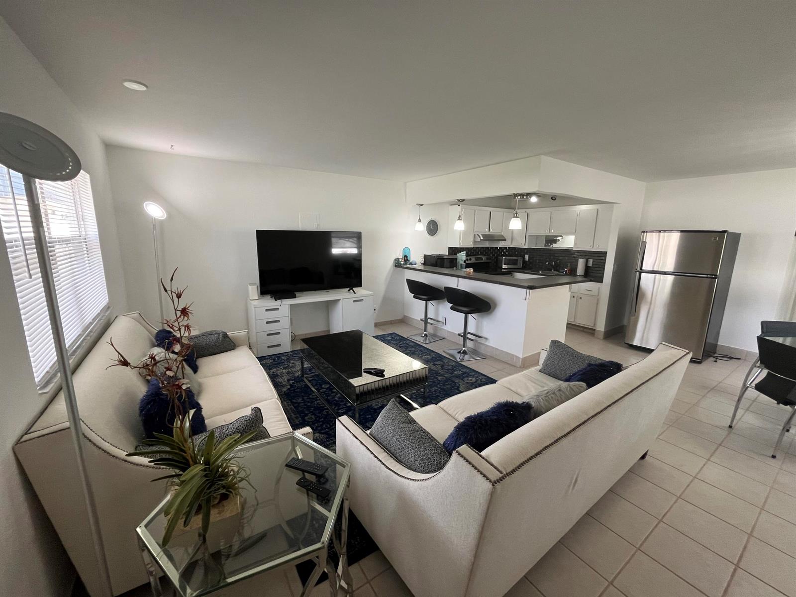 A living room with two white sofas, a mirrored coffee table, and an open kitchen — 114 Waterford E # 114, Delray Beach FL 33446, DELRAY BEACH, FL