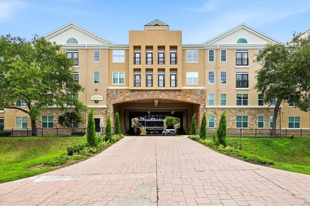 A paved driveway leads to the arched entrance of a multi-story apartment building with stone accents — 4221 W SPRUCE STREET UNIT 1419, TAMPA, FL