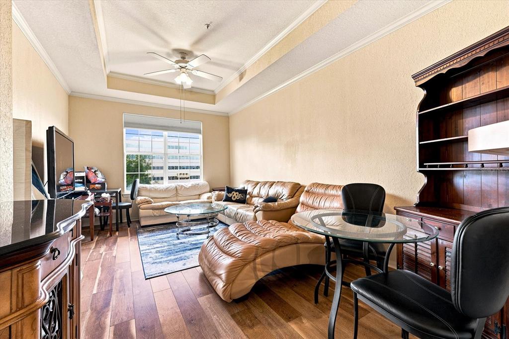 A living room features a leather sectional, a glass dining table, and wood-look flooring — 4221 W SPRUCE STREET UNIT 1419, TAMPA, FL