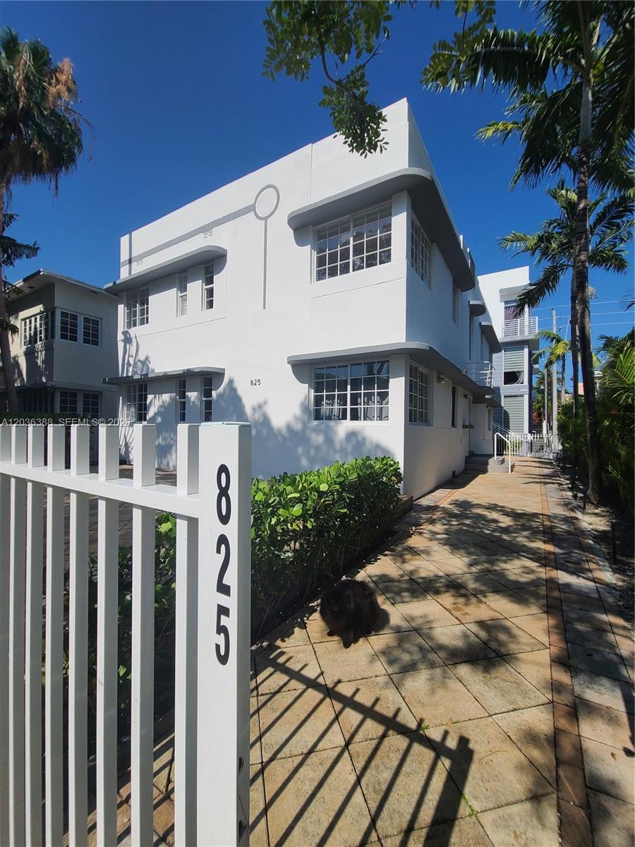 A white two-story Art Deco building features a fenced walkway and a small black cat — 825 Michigan Ave # 3, Miami Beach FL 33139, MIAMI BEACH, FL