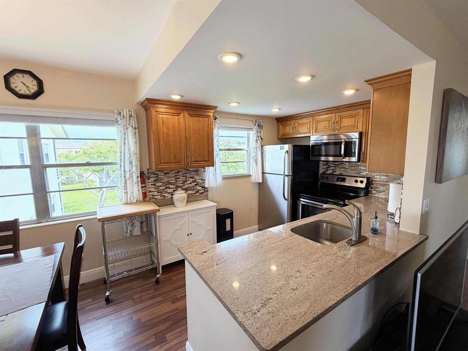 A kitchen features wood cabinets, granite countertops, stainless steel appliances, and a dining area — 375 Mansfield I, Boca Raton FL 33434, BOCA RATON, FL