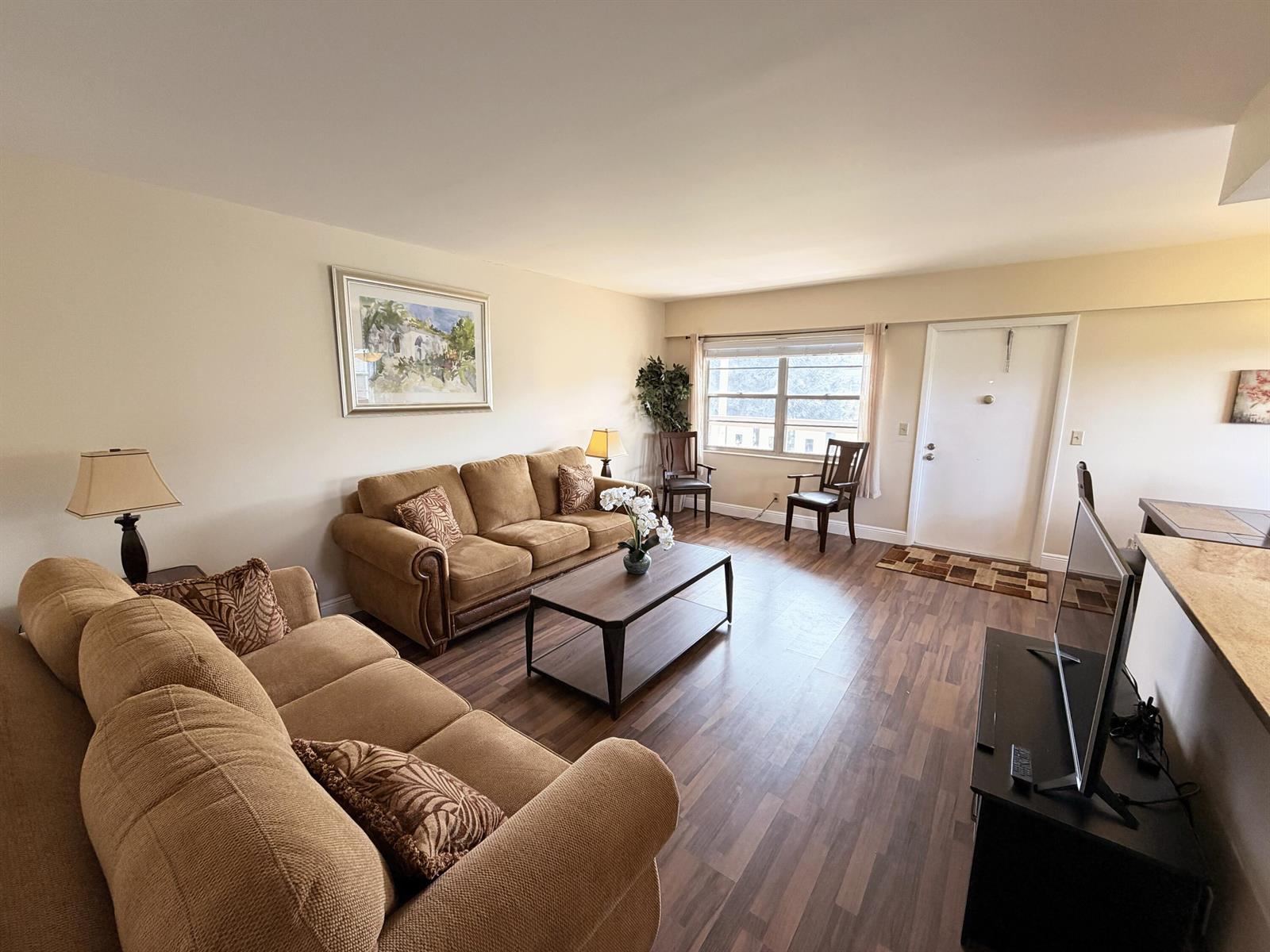 A living room features brown sofas, a coffee table, wood-look flooring, and a front door — 375 Mansfield I, Boca Raton FL 33434, BOCA RATON, FL