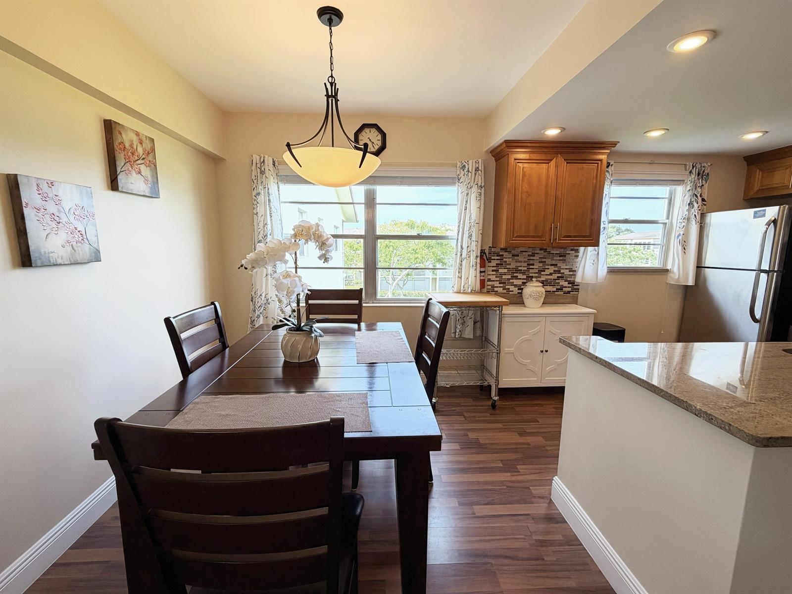 A dining area with a wooden table and chairs sits adjacent to a kitchen — 375 Mansfield I, Boca Raton FL 33434, BOCA RATON, FL
