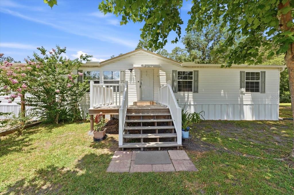 A white single-story manufactured home with a wooden front porch and stairs — 10626 PATHFINDER TRAIL, LAKELAND, FL