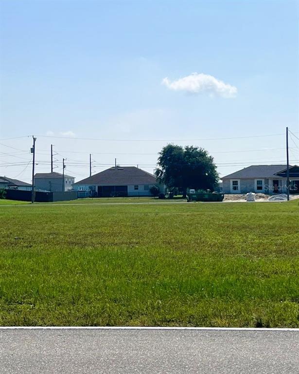 A grassy vacant lot sits in front of several suburban houses under a blue sky — 2713 SANTA BARBARA BOULEVARD N, CAPE CORAL, FL