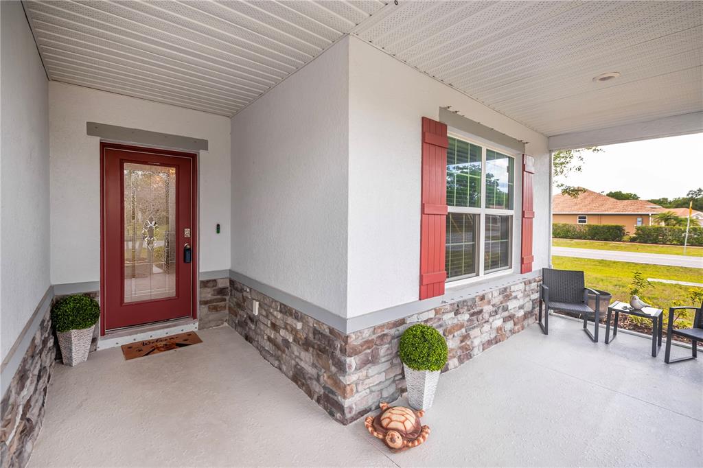 A covered front porch features a red door, stone veneer siding, and red window shutters — 640 ENCARNACION STREET, PUNTA GORDA, FL