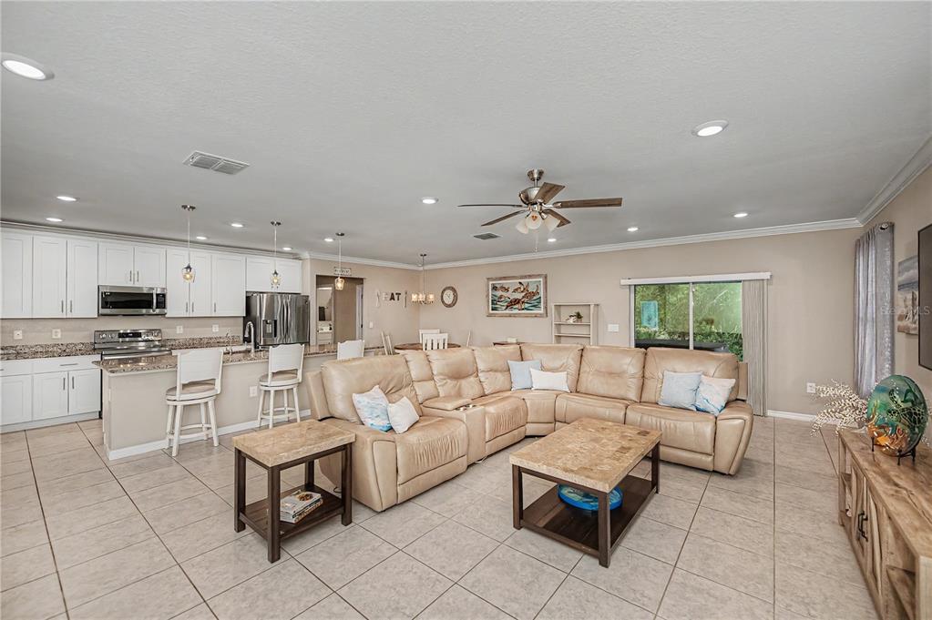 An open-concept kitchen and living area features white cabinetry, tile flooring, and a sectional sofa — 640 ENCARNACION STREET, PUNTA GORDA, FL