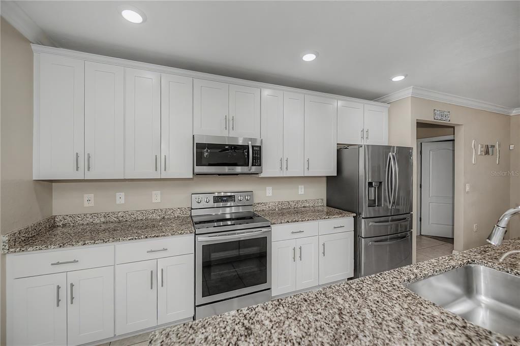 A kitchen features white cabinets, granite countertops, and stainless steel appliances — 640 ENCARNACION STREET, PUNTA GORDA, FL