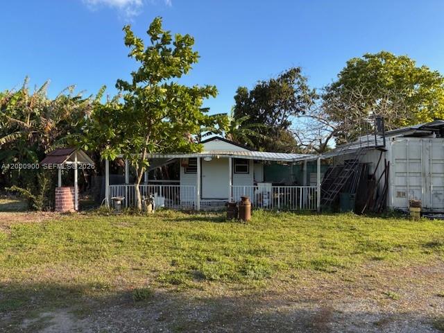A small house with a white porch sits on a grassy lot with trees — UNINCORPORATED, Miami FL 33187, MIAMI, FL
