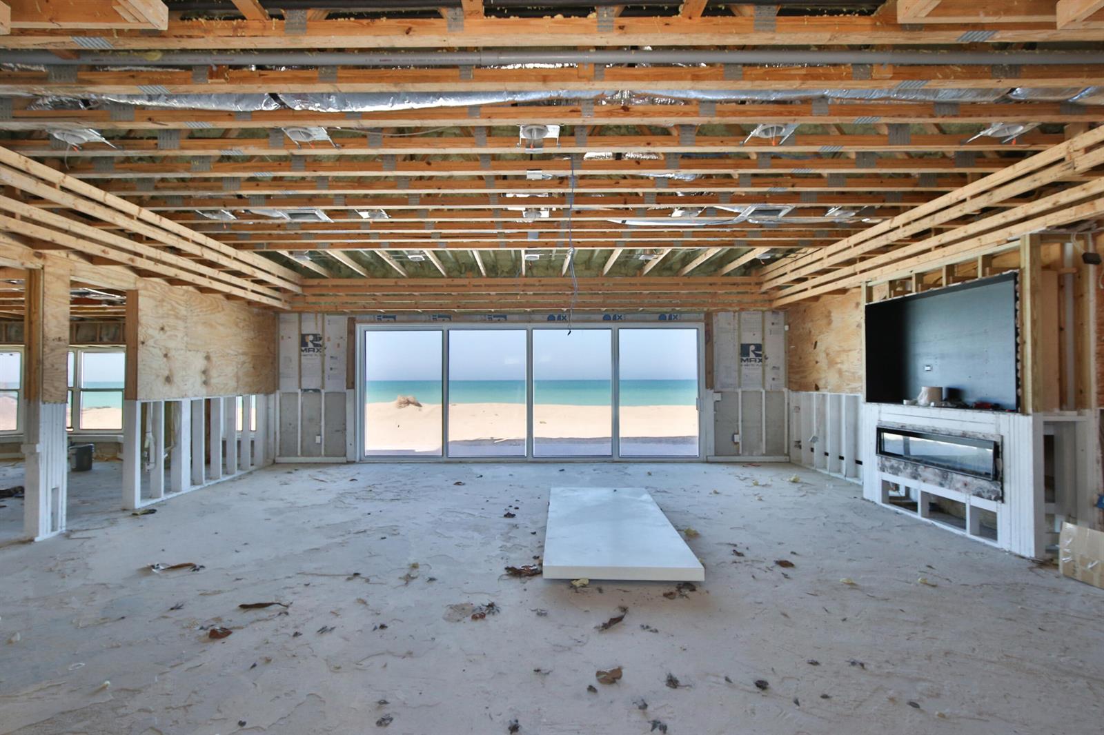 An unfinished room with exposed ceiling joists, wall studs, and a large sliding glass door — 7816 Sanderling Road, Sarasota FL 34242, SARASOTA, FL