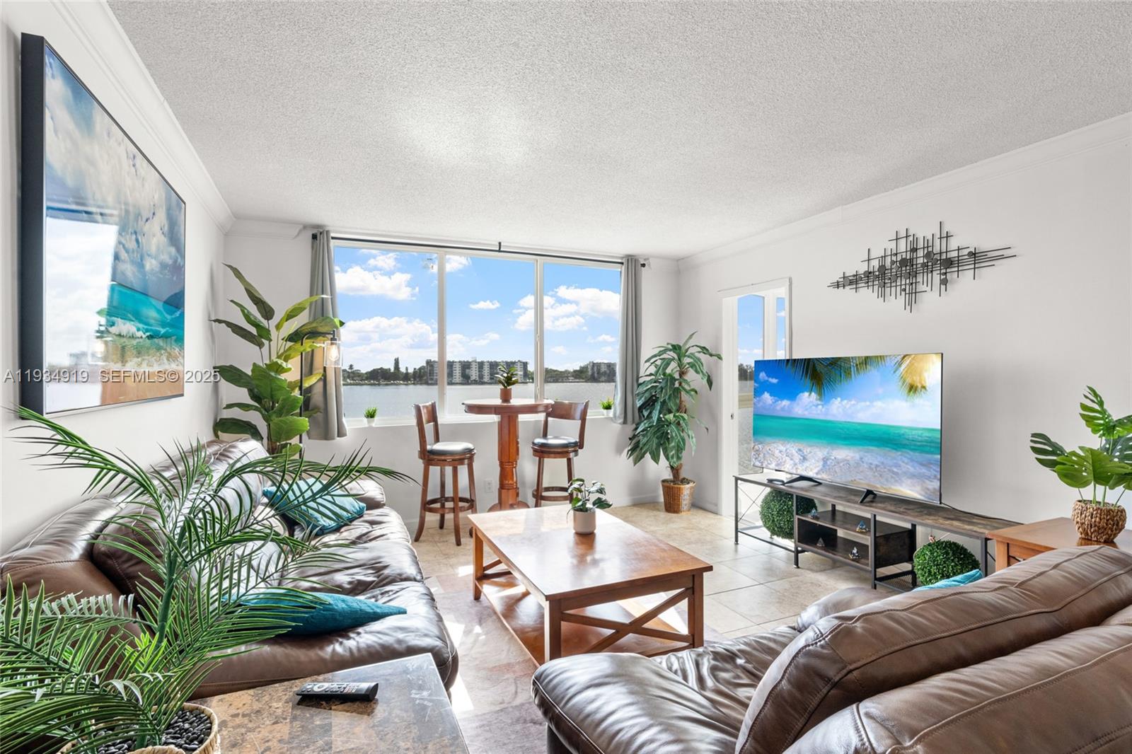 A living room features brown leather sofas, a wooden coffee table, and a waterfront view — 1170 NE 191st St # 35, Miami FL 33179, MIAMI, FL