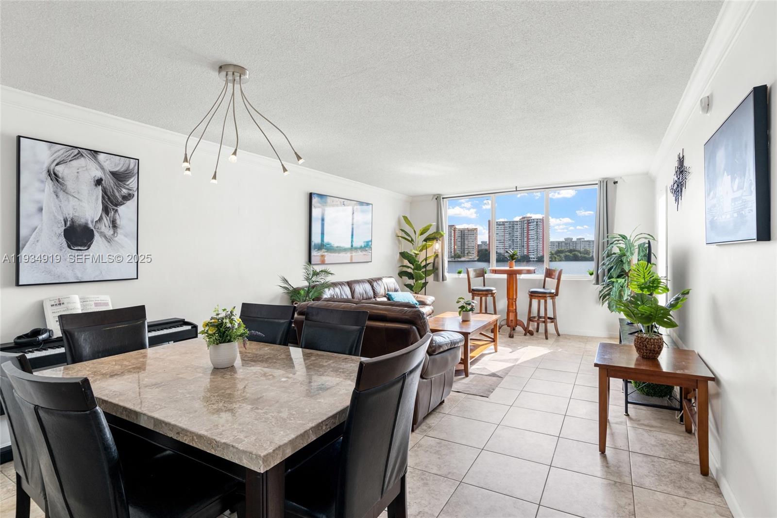 A living and dining area features tile floors, a marble-topped table, and a waterfront view — 1170 NE 191st St # 35, Miami FL 33179, MIAMI, FL