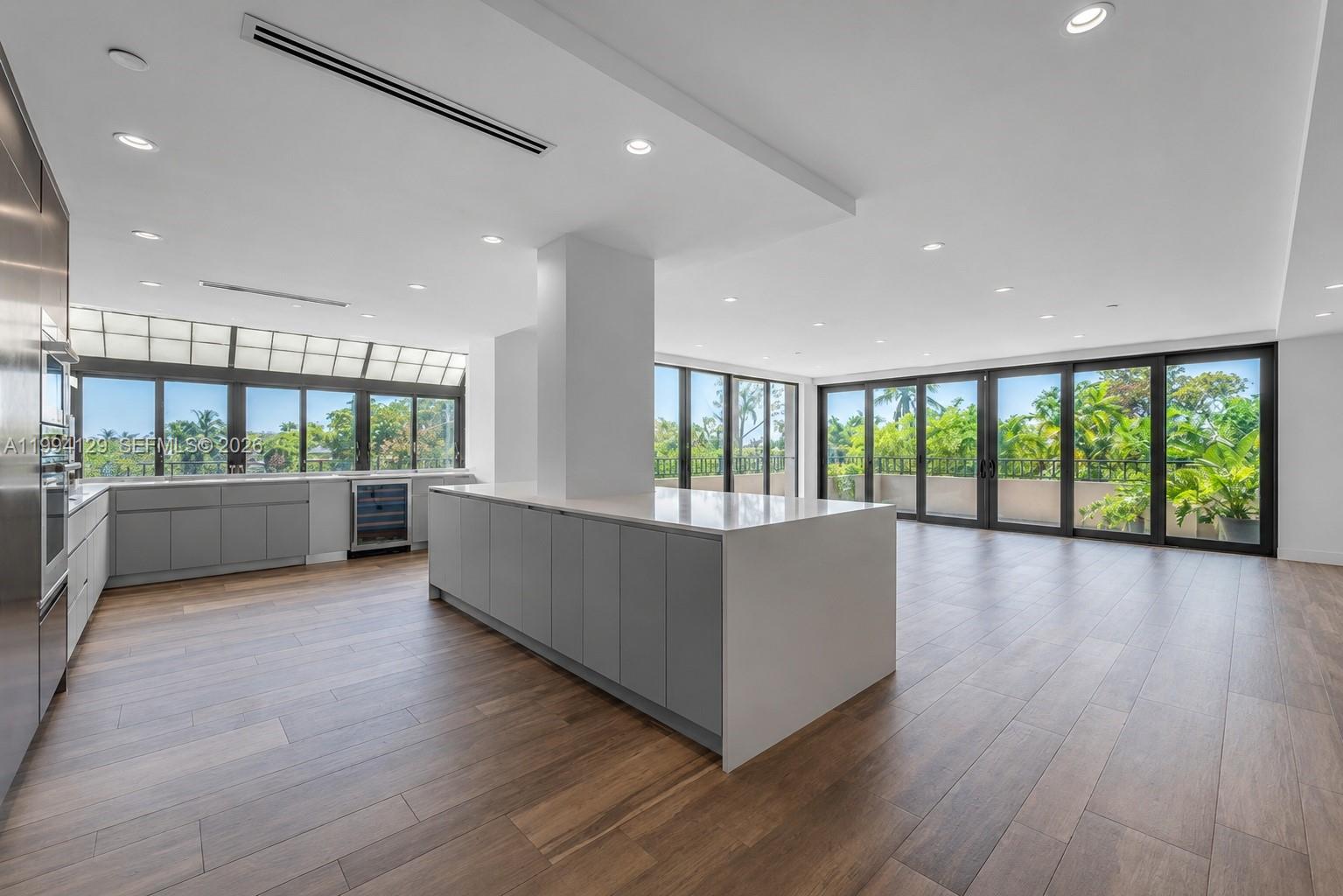 A modern kitchen with a large island, gray cabinetry, and floor-to-ceiling windows overlooking greenery — 151 Crandon Blvd # 345, Key Biscayne FL 33149, KEY BISCAYNE, FL