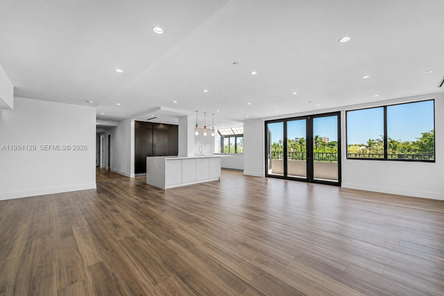 A modern open-concept living area features a kitchen island, dark cabinetry, and large glass doors — 151 Crandon Blvd # 345, Key Biscayne FL 33149, KEY BISCAYNE, FL