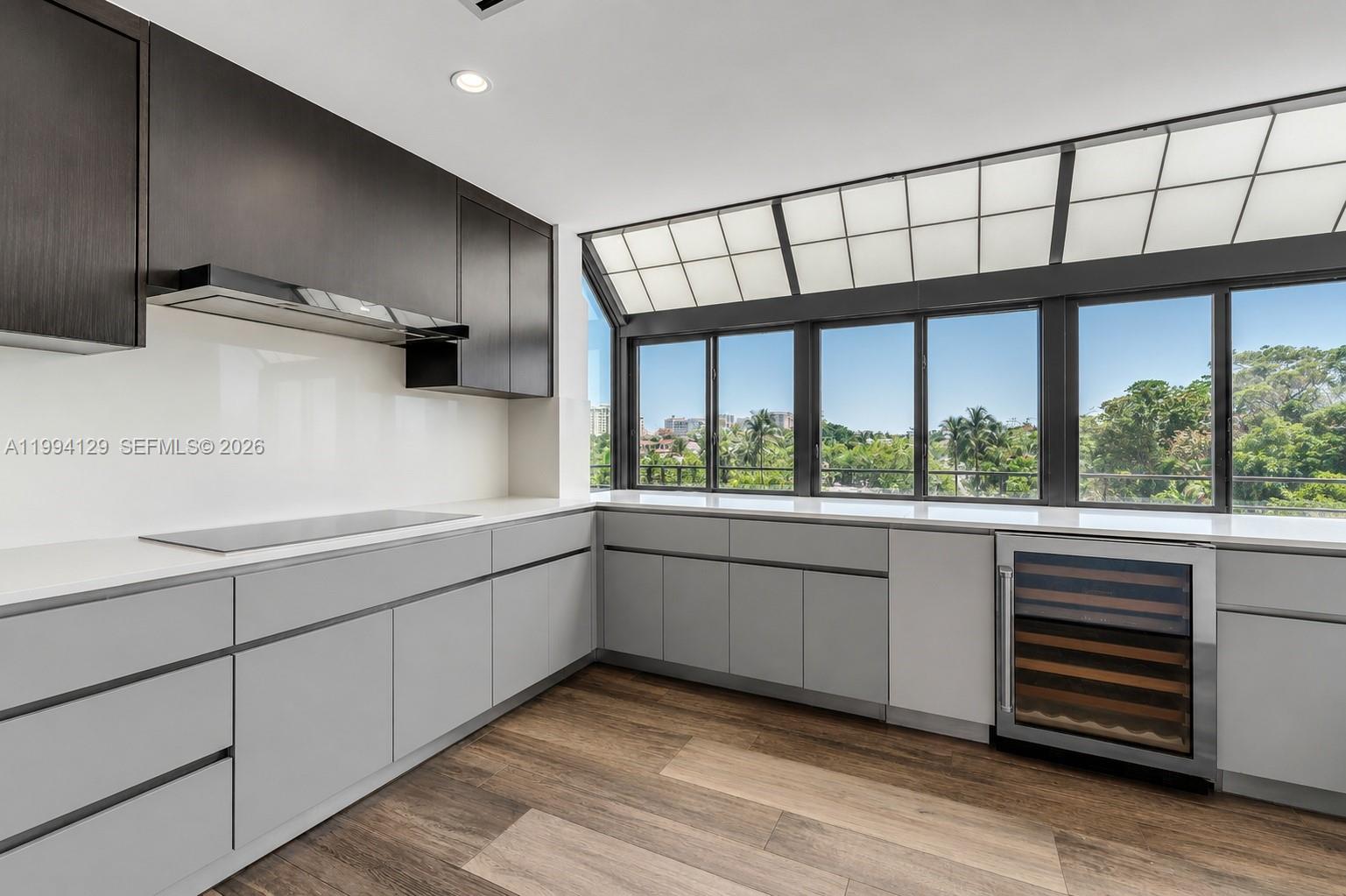 A modern kitchen features gray lower cabinets, dark upper cabinets, and a wine refrigerator — 151 Crandon Blvd # 345, Key Biscayne FL 33149, KEY BISCAYNE, FL