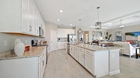 A bright, open-concept kitchen features white cabinetry, granite countertops, and a large central island — 3280 ALTIMIRA DRIVE, FORT MYERS, FL