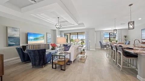 An open-concept living room and kitchen area with light tile flooring and modern light fixtures — 3280 ALTIMIRA DRIVE, FORT MYERS, FL