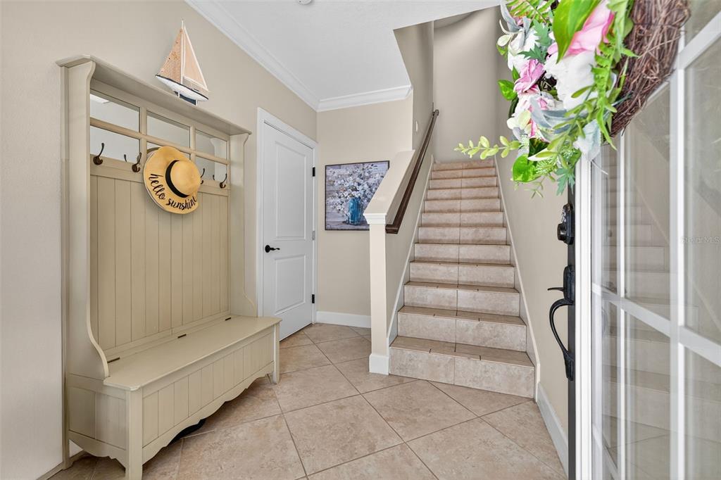 An entryway features a beige hall tree, tiled floors, and a staircase with tiled steps — 6080 MOORINGS DRIVE S, ST PETERSBURG, FL