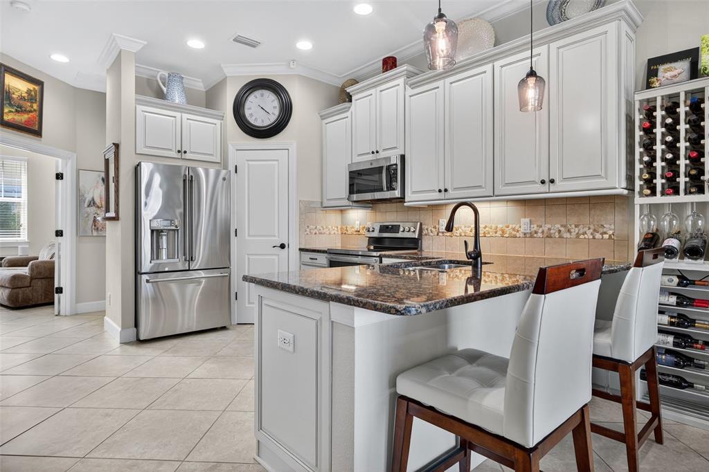 A kitchen features white cabinets, granite countertops, stainless steel appliances, and a wine rack — 6080 MOORINGS DRIVE S, ST PETERSBURG, FL