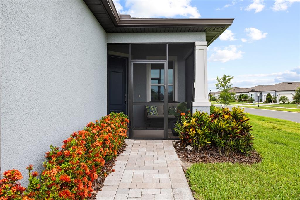 A paved walkway leads to a screened-in front porch with a dark door and landscaping — 9454 BALLASTER POINTE LOOP, PARRISH, FL