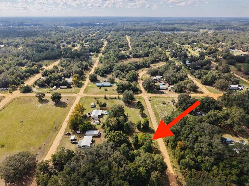 An aerial view shows a wooded, undeveloped lot bordered by dirt roads in a rural area — 208 N HELMERS AVENUE, INTERLACHEN, FL