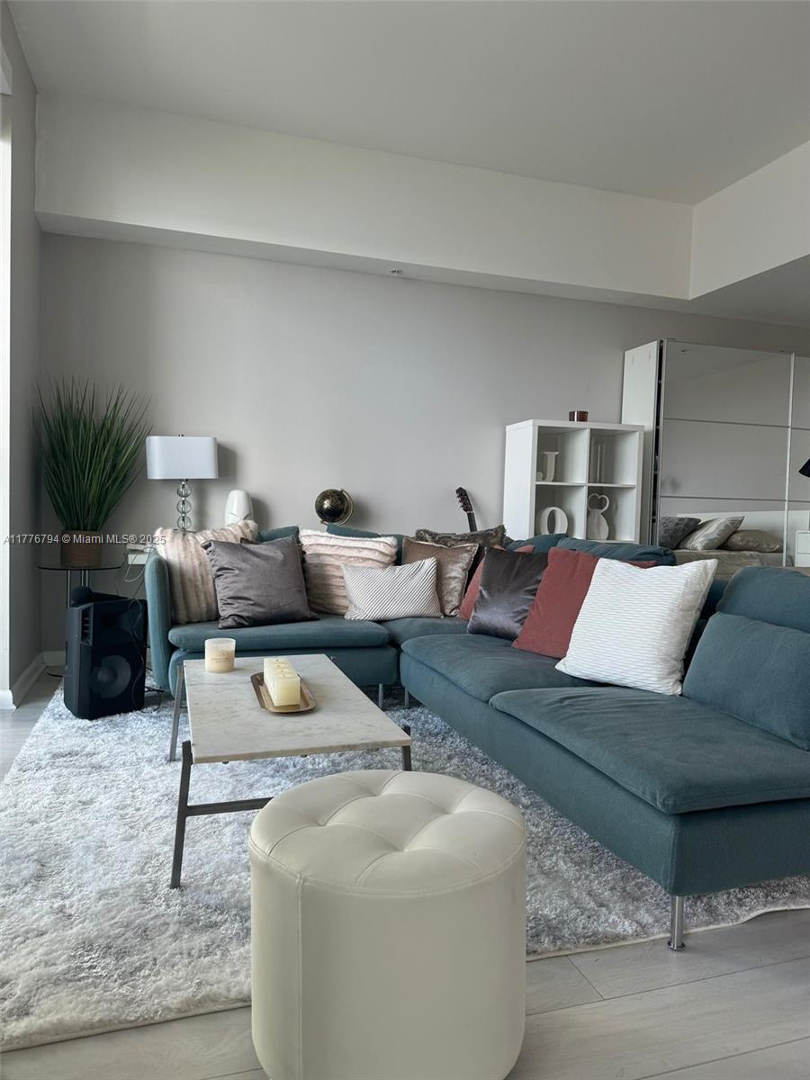 A living room features a teal sectional sofa, a marble coffee table, and a white ottoman — 244 Biscayne Blvd # 3905, Miami FL 33132, MIAMI, FL