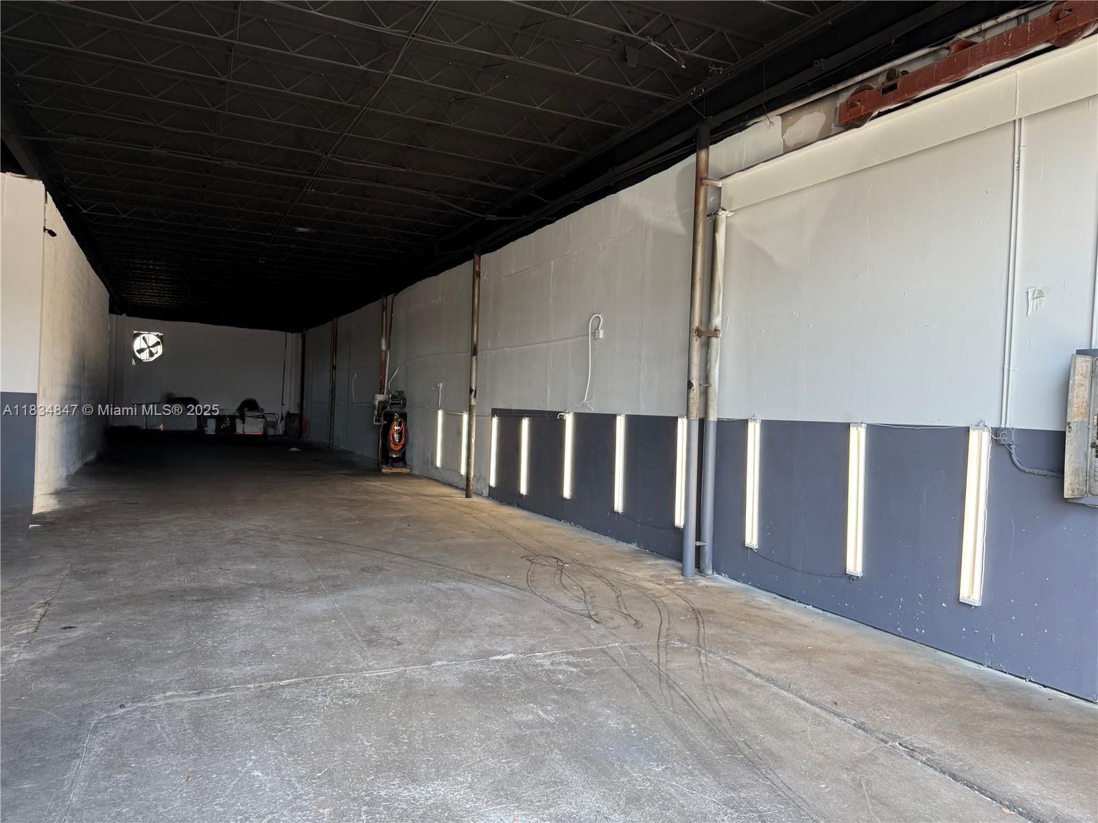 An empty industrial warehouse space features a black ceiling, concrete floors, and wall-mounted vertical lights — 3771 NW 51st St # B, Hialeah FL 33142, HIALEAH, FL