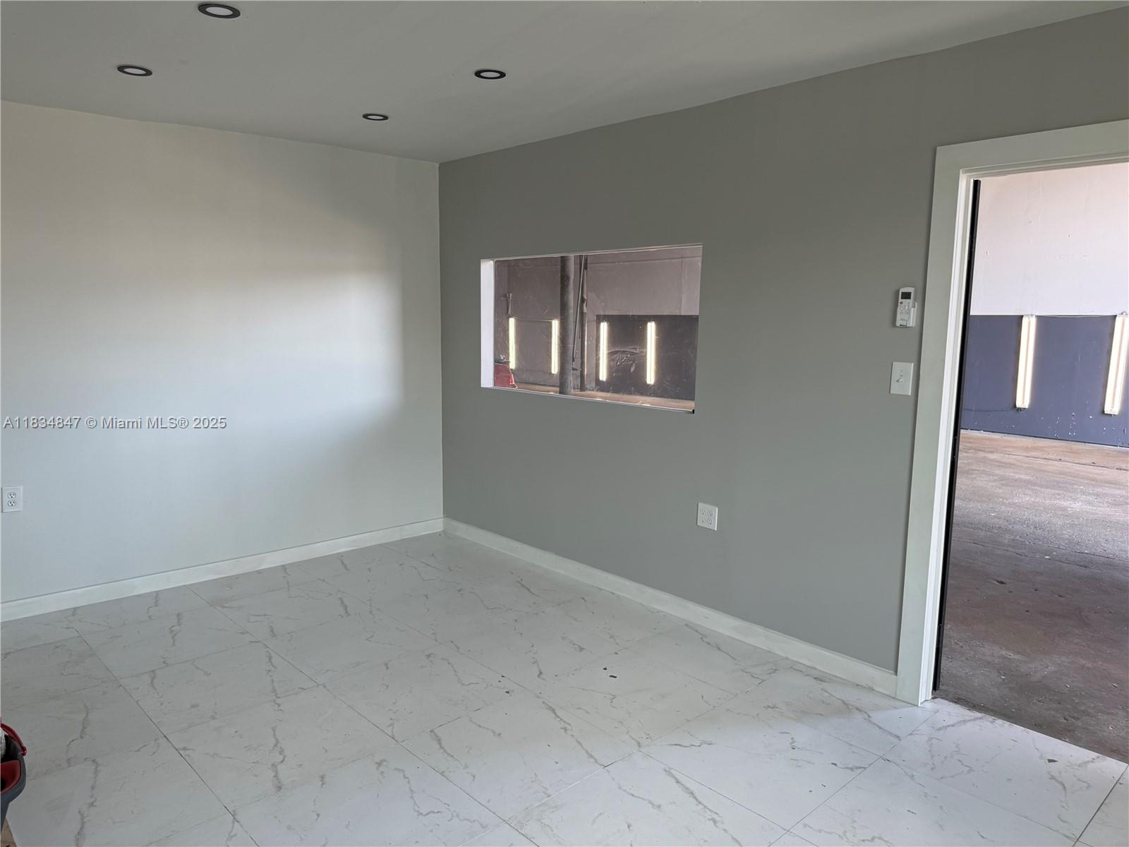 A room with white marble-patterned tile floors, gray walls, and a rectangular interior window — 3771 NW 51st St # B, Hialeah FL 33142, HIALEAH, FL