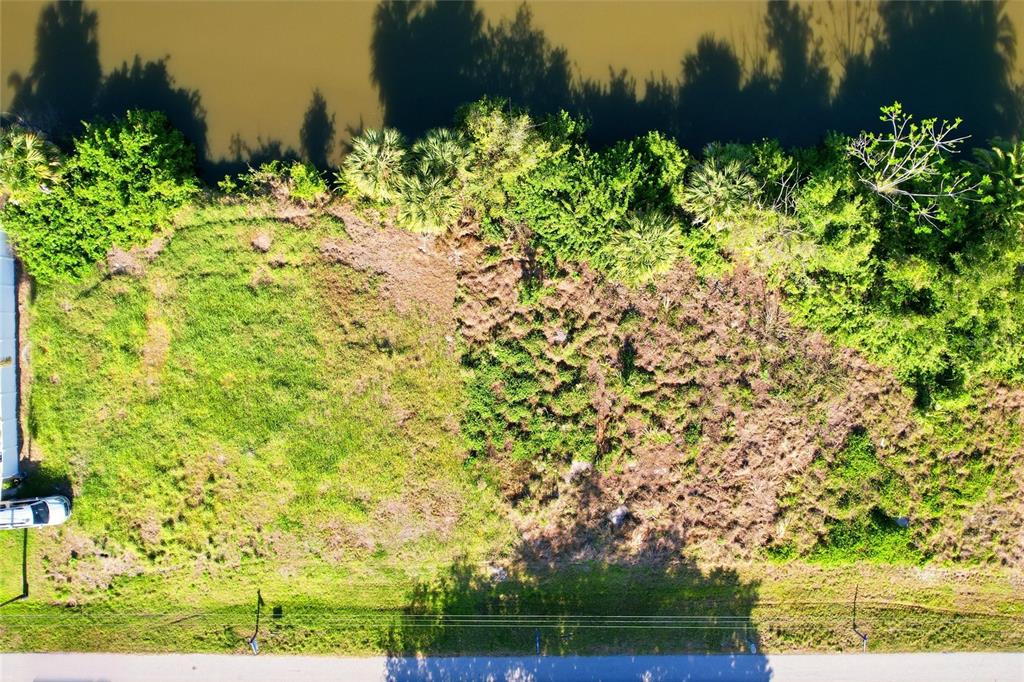 An aerial view of a vacant, partially cleared grassy lot bordering a body of water — 3383 DESOTO DRIVE, PUNTA GORDA, FL
