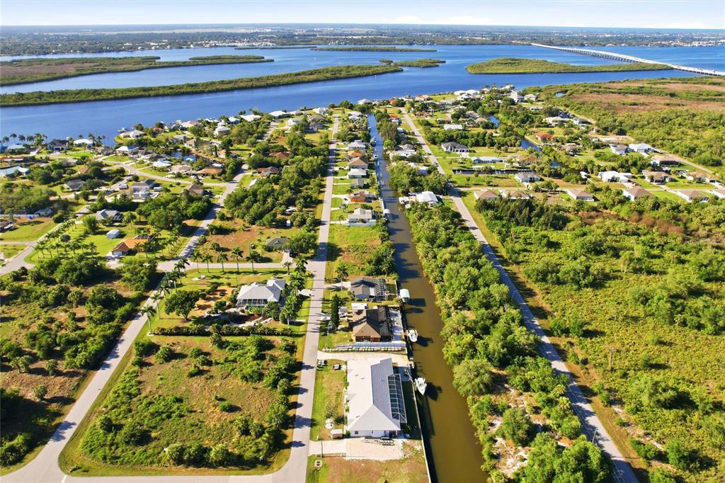 An aerial view shows a residential neighborhood with houses along a canal near water — 3383 DESOTO DRIVE, PUNTA GORDA, FL