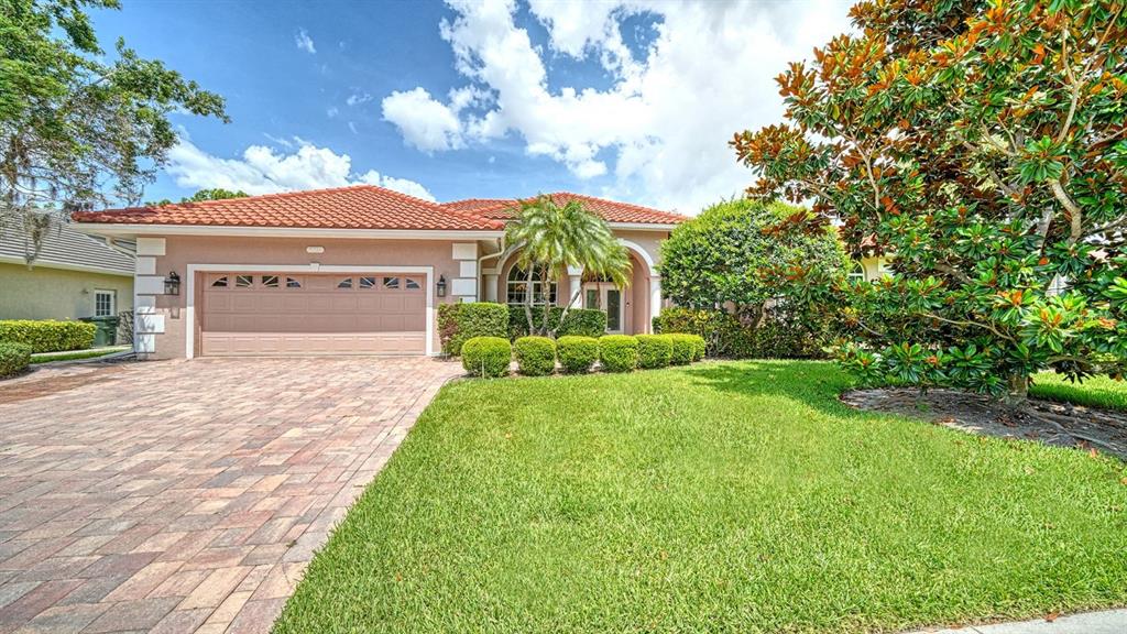 A single-story house with a tiled roof, a paved driveway, and a manicured front lawn — 4769 SWEETMEADOW CIRCLE, SARASOTA, FL