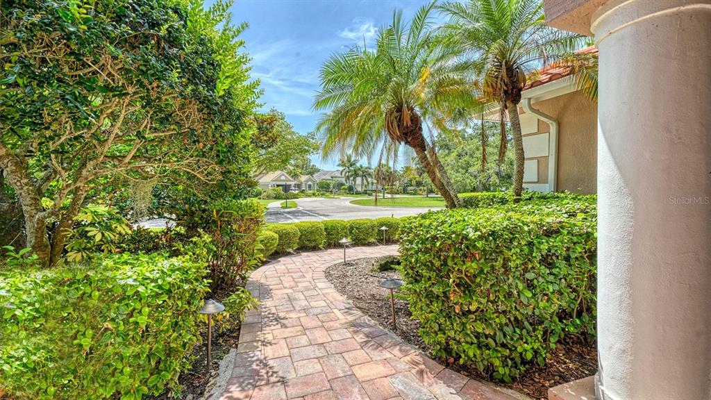 A stone walkway leads through a landscaped yard toward a street in a residential neighborhood — 4769 SWEETMEADOW CIRCLE, SARASOTA, FL