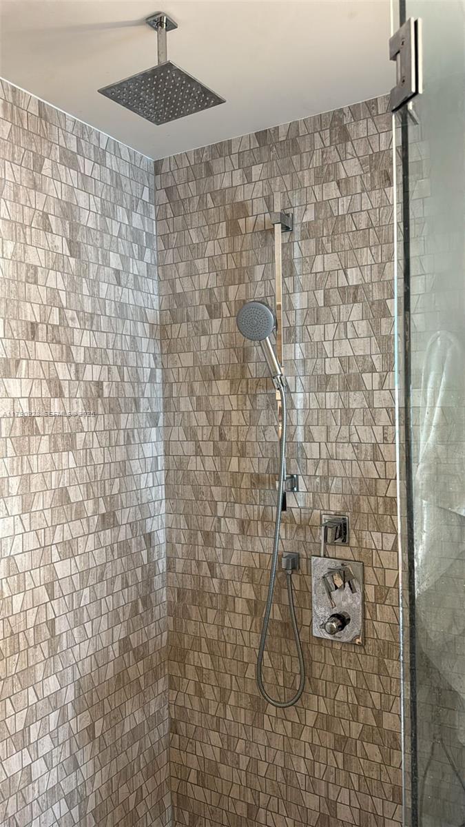 A shower stall features a rainfall showerhead, a handheld sprayer, and beige geometric wall tiles — 88 SW 7th St # 810, Miami FL 33130, MIAMI, FL