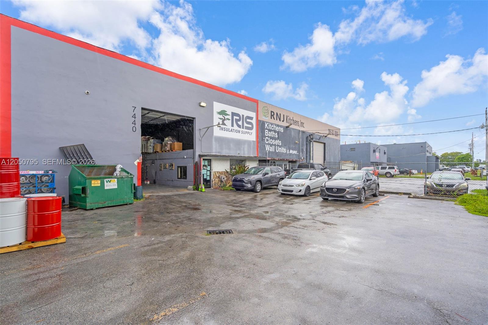 The exterior of a commercial warehouse building features a large bay door and parking lot — 7440 NW 66th St, Miami FL 33166, MIAMI, FL
