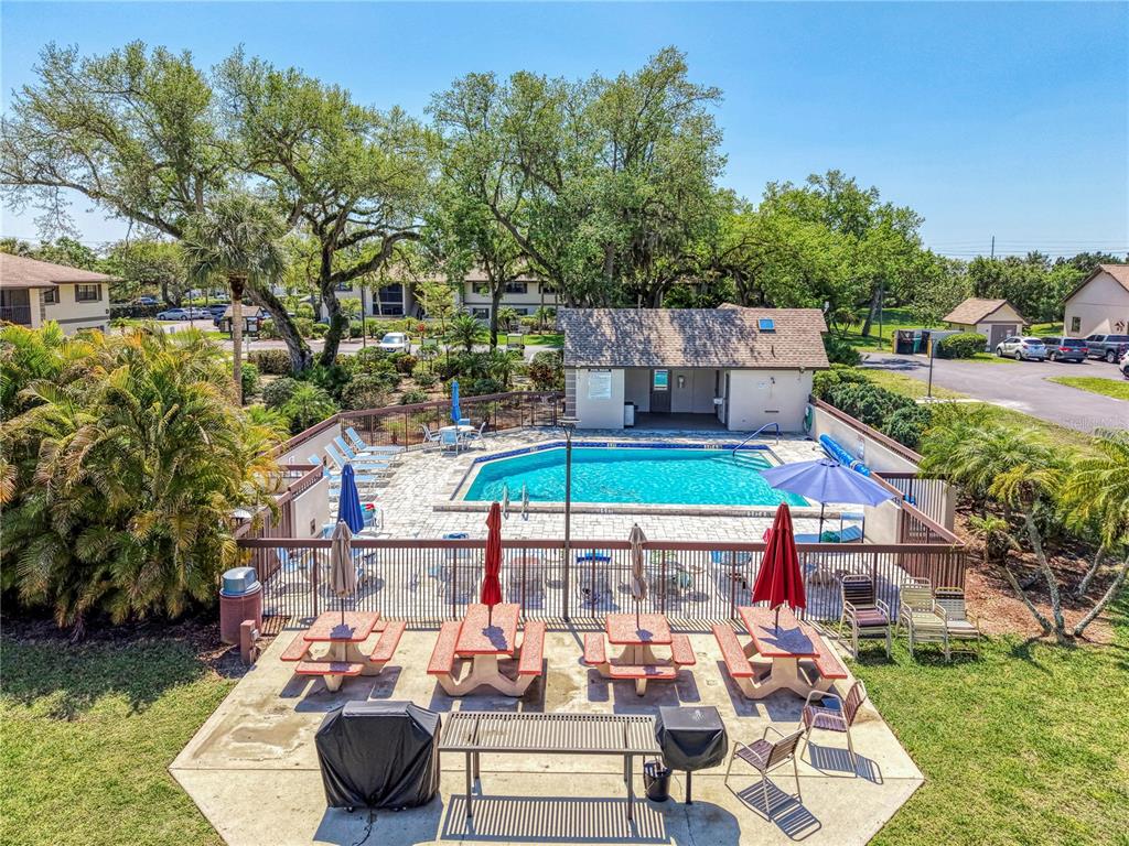 An outdoor swimming pool area features picnic tables, grills, and a small pool house building — 1515 FORREST NELSON BOULEVARD UNIT G104, PORT CHARLOTTE, FL