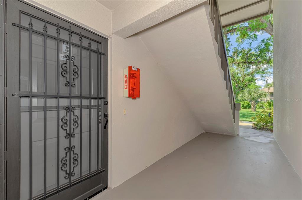 A gray security door and a red fire alarm box are located on a covered walkway — 1515 FORREST NELSON BOULEVARD UNIT G104, PORT CHARLOTTE, FL