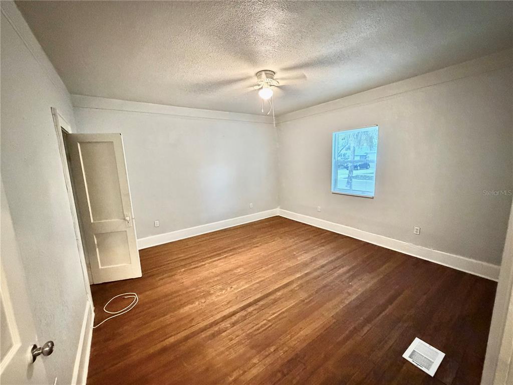 An empty bedroom features hardwood floors, light gray walls, a ceiling fan, and a window — 4700 10TH AVENUE S, ST PETERSBURG, FL