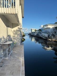 A view from a patio overlooking a narrow canal lined with houses and docked boats — 75 Coral Dr, Key Largo FL 33037, KEY LARGO, FL