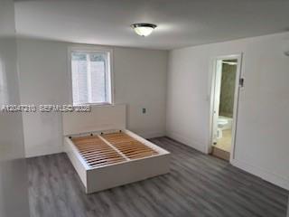 A bedroom features a white platform bed frame, grey wood-look flooring, and an attached bathroom — 75 Coral Dr, Key Largo FL 33037, KEY LARGO, FL