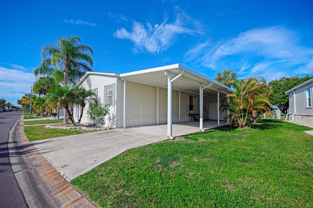 A single-story manufactured home features light-colored siding, a concrete driveway, and a covered carport — 2100 KINGS HIGHWAY UNIT 364, PORT CHARLOTTE, FL
