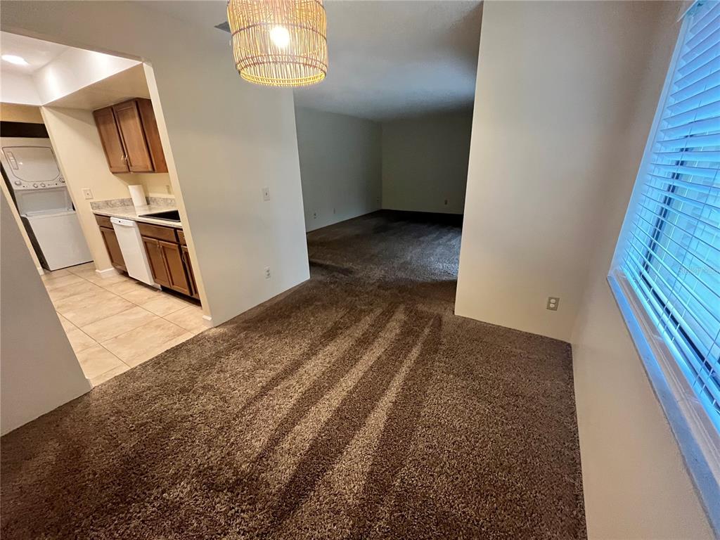 A dining area with brown carpet leads into a kitchen with tile flooring and wood cabinets — 308 PALM COAST PARKWAY NE UNIT 203, PALM COAST, FL