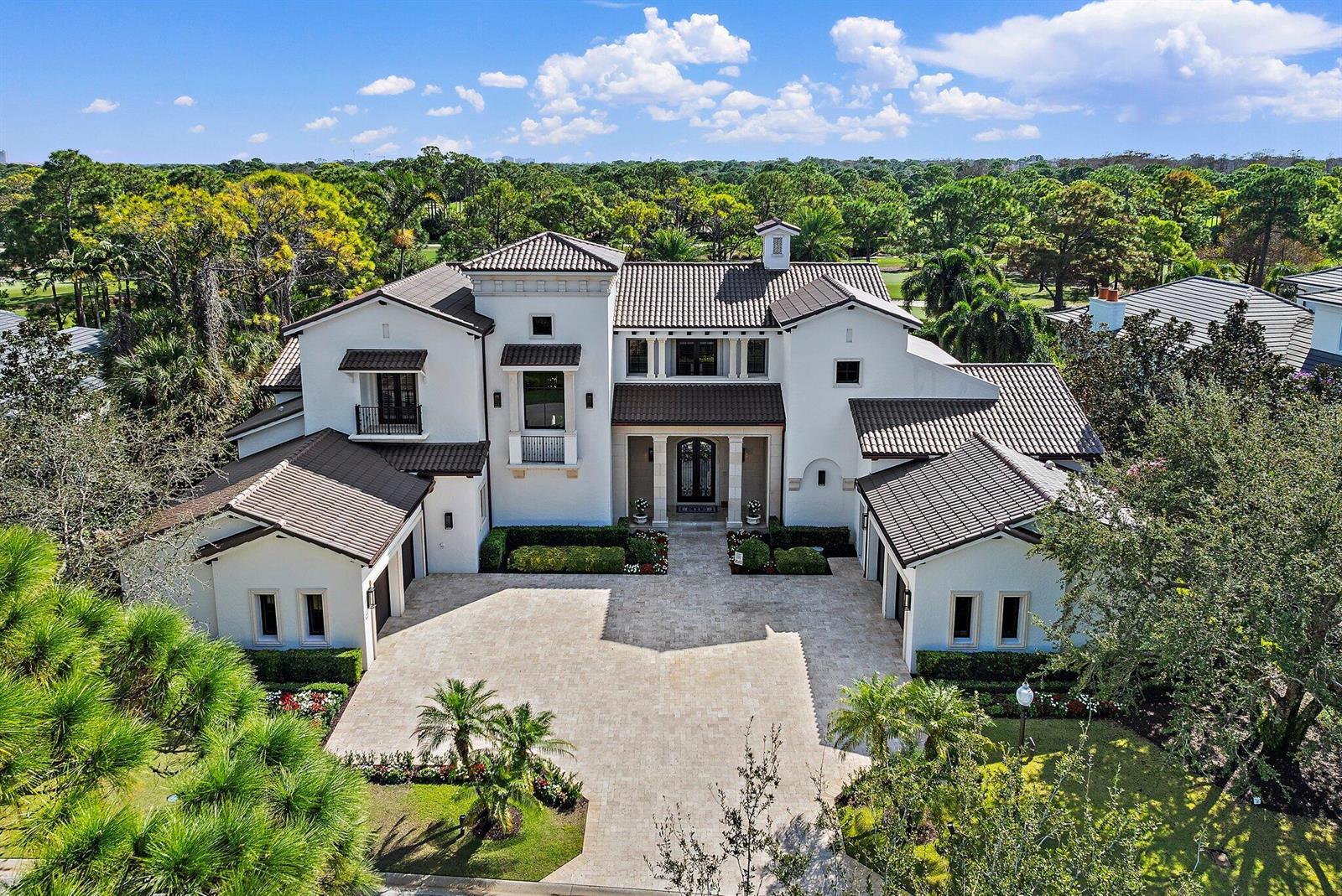 An aerial view of a large white Mediterranean-style house with a tiled roof and driveway — 135 W Bears Club Drive, Jupiter FL 33477, JUPITER, FL